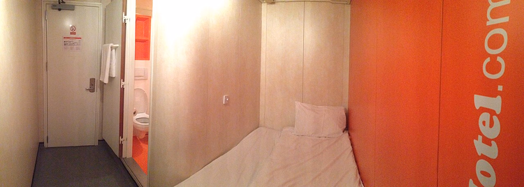 Camera angusta dell'easyHotel con parete arancione brandizzata