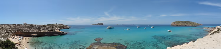 İbiza'da kayalıklar ve teknelerle turkuaz koy