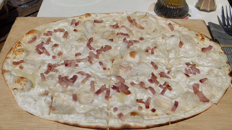 Klassieke tarte flambée met spek op een houten plank