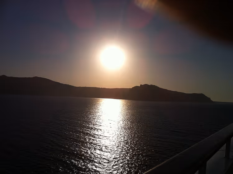 Sonnenuntergang über dem Meer und die dunkle Silhouette der Küste