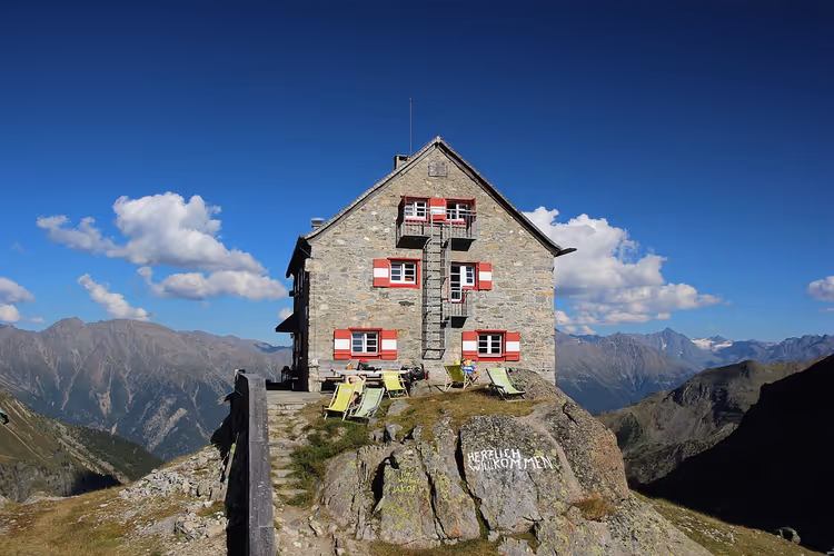 Кам'яна хижа Erlanger Hütte з червоними віконницями в горах