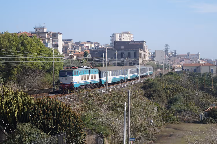 Arka planda Acireale kasabasıyla tren