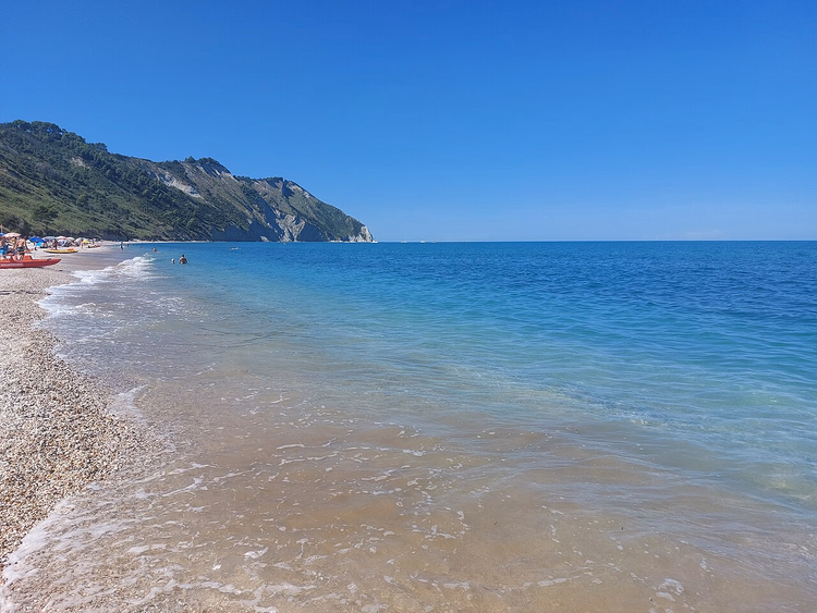 spiaggia di ciottoli e scogliere bianche sopra acqua turchese