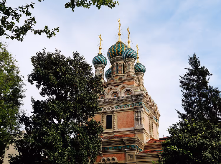 Церковь с разноцветными луковичными куполами среди деревьев