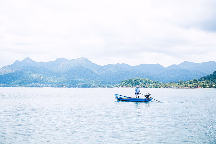 Visser in een boot voor de bergachtige kust van Ko Chang