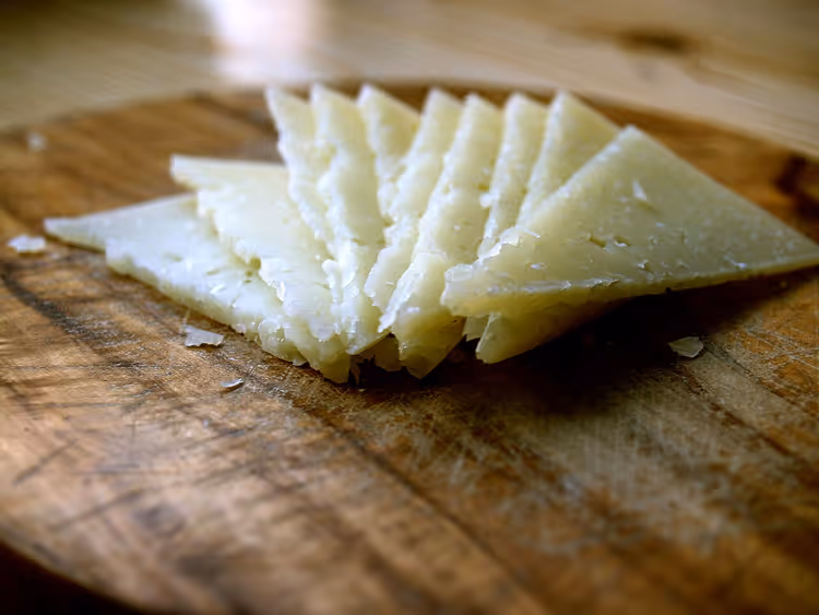 Ahşap bir tahtada ince dilimlenmiş Manchego peyniri