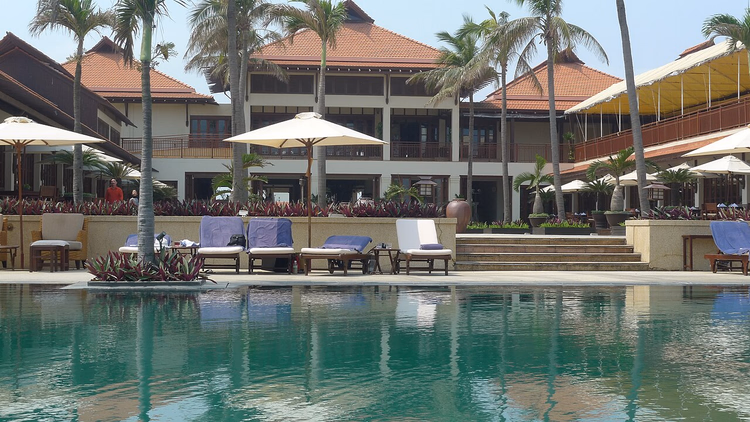 Zwembad en gebouwen van Furama Resort onder palmbomen