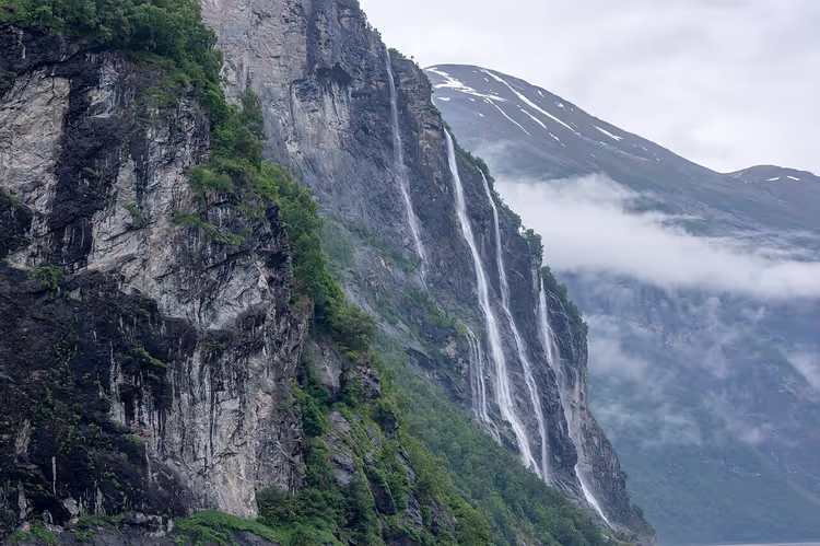 Tynne fossefallstråler på klippene i Geirangerfjorden