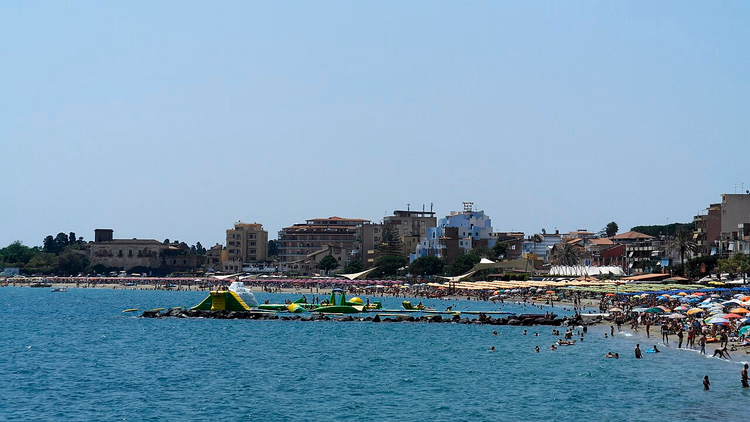 Zandstrand van Giardini Naxos met parasols in de zomer