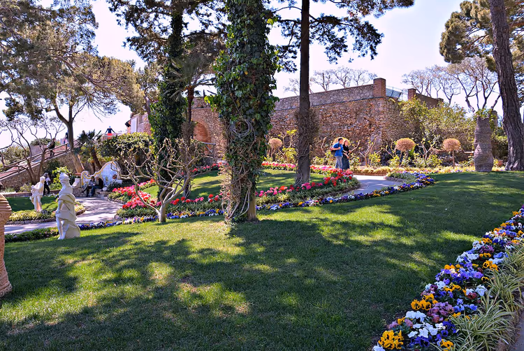 Park med blomsterbed, plen, trær og besøkende