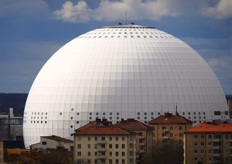 Witte bolvormige Avicii Arena tussen de daken van de stad