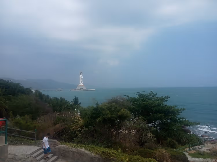 Wit standbeeld van Guanyin in de zee, gezien vanaf de kust