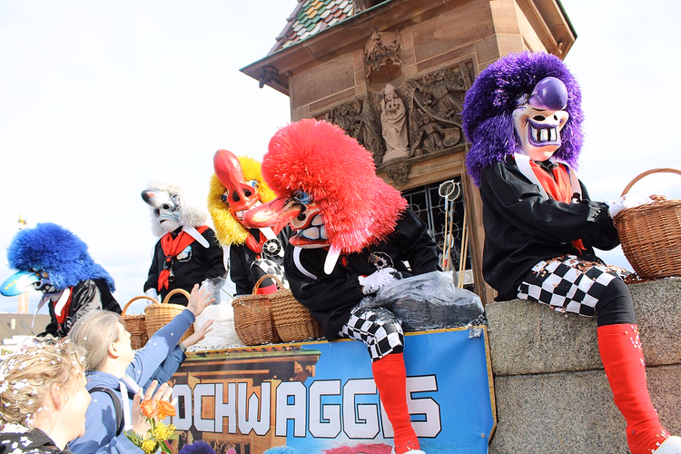 Waggis auf einem Fasnachtswagen, der Kindern Süßigkeiten zuwirft