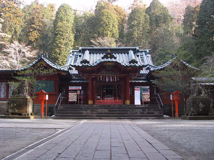 Rotes Gebäude des Hakone-Schreins zwischen hohen Bäumen