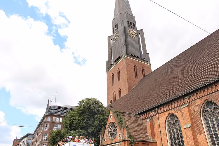 Teglsteinskirke med tårn, klokke og grønn spir