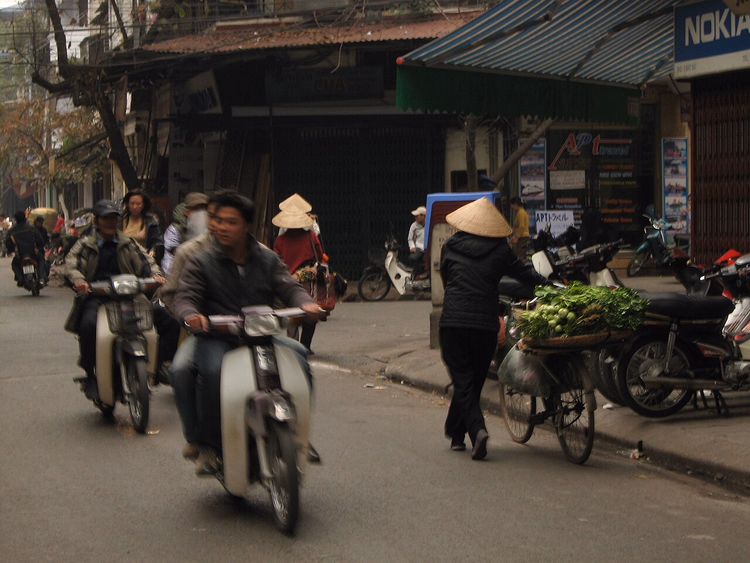 Straße in Hanoi: Mopeds und eine Händlerin mit Kegelhut