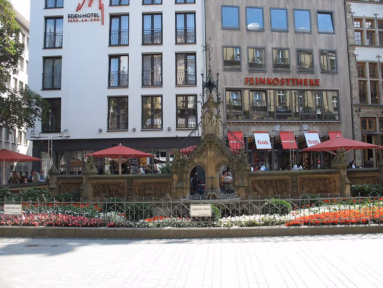 Heinzelmännchenbrunnen mit Blumenbeeten auf einem Kölner Platz