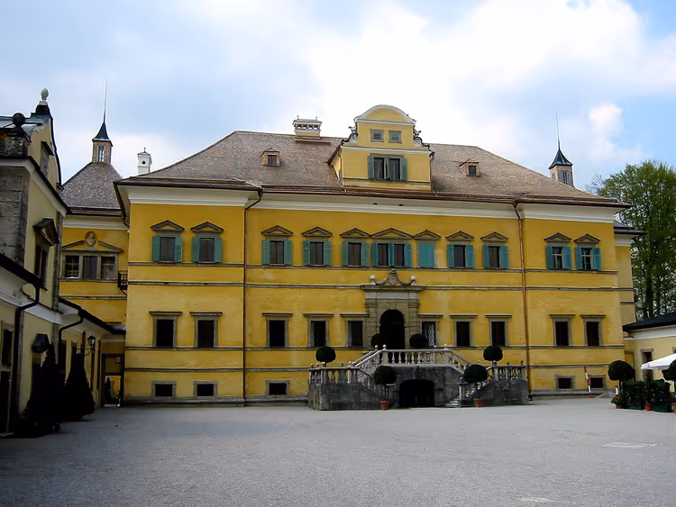 Den gule barokkfasaden til slottet Hellbrunn med gårdsplass