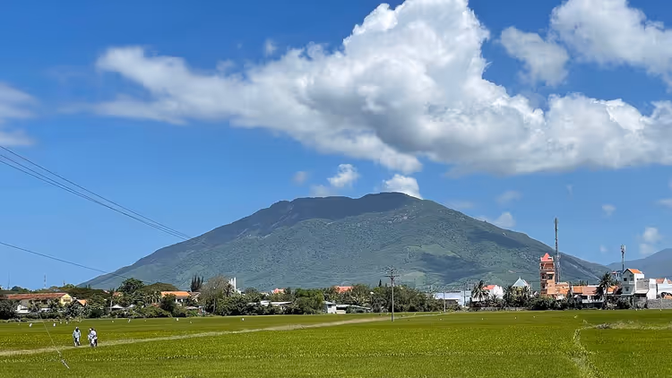 Bulutlar altında yeşil tarlalar ve Hon Heo Dağı