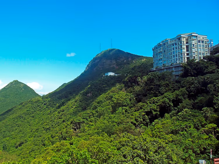 Groene hellingen en Victoria Peak met een hoog gebouw