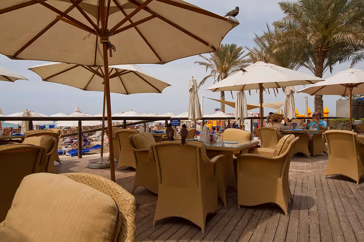 Terras van beachclub met parasols en rotan meubels