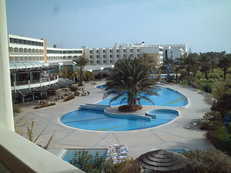 Basen z palmami przy budynkach hotelu