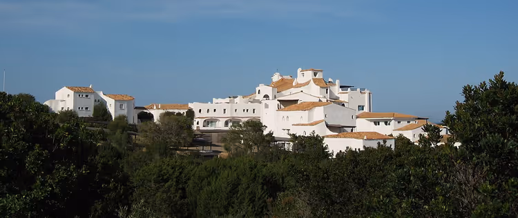 ağaçlar arasında bir tepede beyaz otel kompleksi