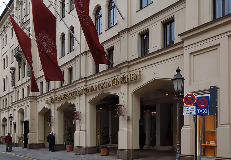 Entrée de l'hôtel Vier Jahreszeiten Kempinski avec drapeaux rouges