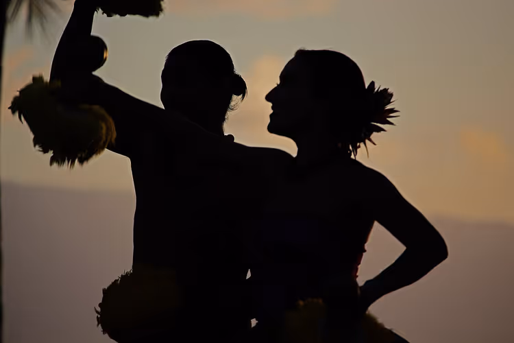 Silhouettes of hula dancers at sunset