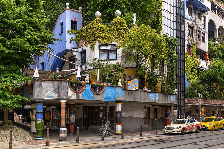 Fargerik fasade på Hundertwasserhaus med søyler og grønt