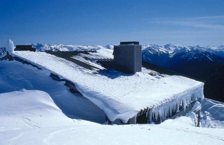Snødekt besøkssenter på Hurricane Ridge med fjell i bakgrunnen