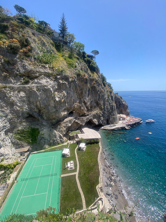 Tennisbane ved foten av en klippe over havet
