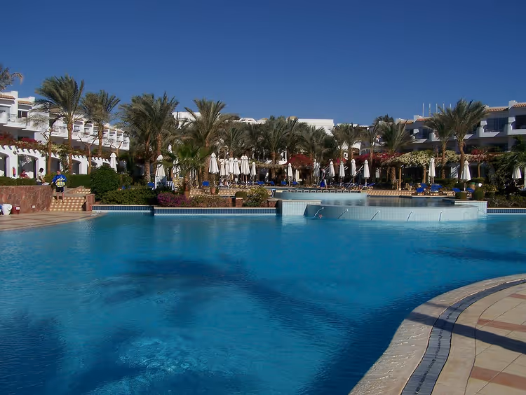 Pool mit Palmen und Gebäuden des Jaz Fanara Resorts