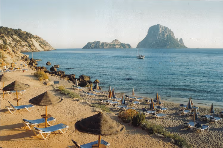 Şemsiyeler ve bir kaya ile Cala d'Hort plajı