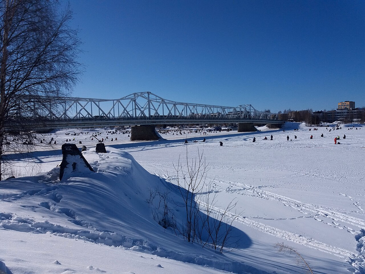 Vissers op het ijs van de rivier bij een brug in Tornio