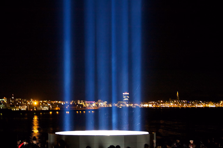 Reykjavik şehir ışıklarına karşı parlayan Imagine Peace Tower ışınları