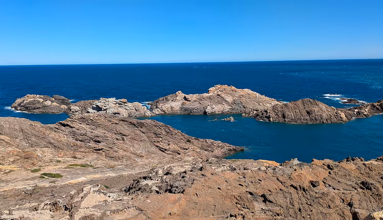 Steinete strand og holme i det blå havet