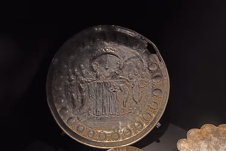 Zilveren pateen met reliëf in een museumvitrine
