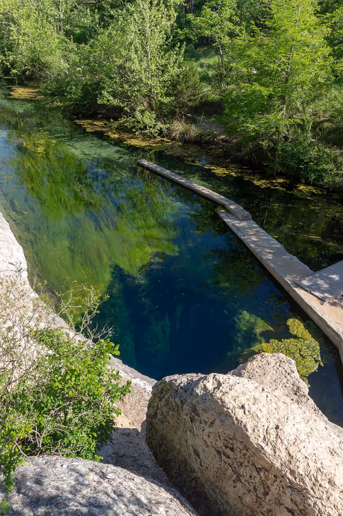 Helder natuurlijk zwemgat met rotsachtige oever en vlonders