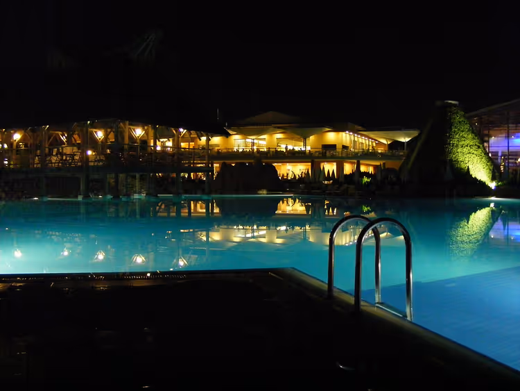 Hotellbasseng om natten og opplyst hotellbygning