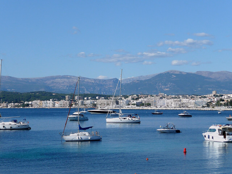 Baai van Juan-les-Pins met jachten en bergen op de achtergrond