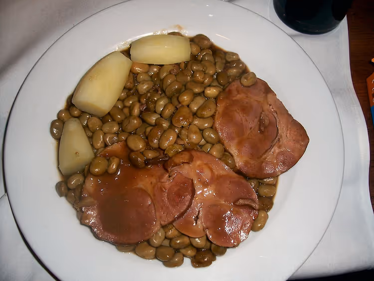 Bord met gerookt varkensvlees, bonen en aardappelen