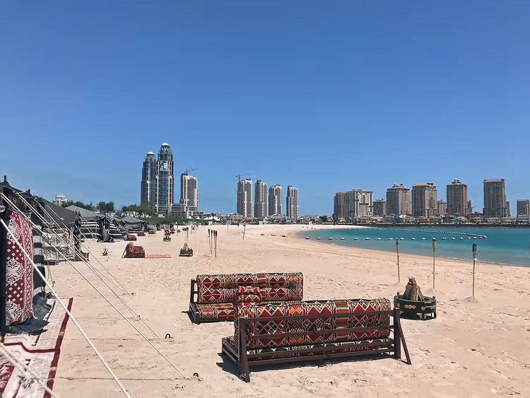 Strand i Qatar med sofaer og utsikt mot Doha-silhuetten