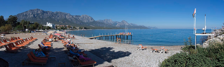 Strand von Kemer mit Sonnenliegen vor den Bergen