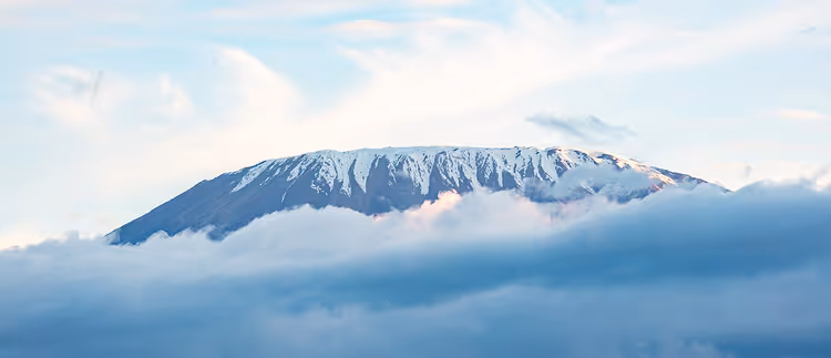 Besneeuwde top van de Kilimanjaro die boven de wolken uitsteekt