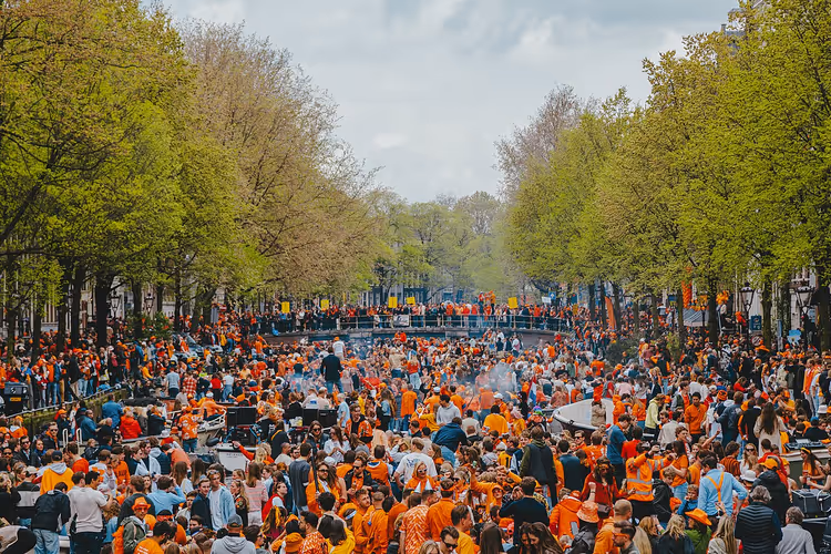 Orange folksamling och Amsterdams kanaler på Koningsdag