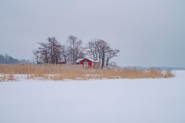 Rood huisje aan een besneeuwde winterkust