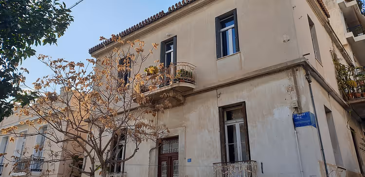 Wohnhaus mit Balkon und einem Baum in Koukaki