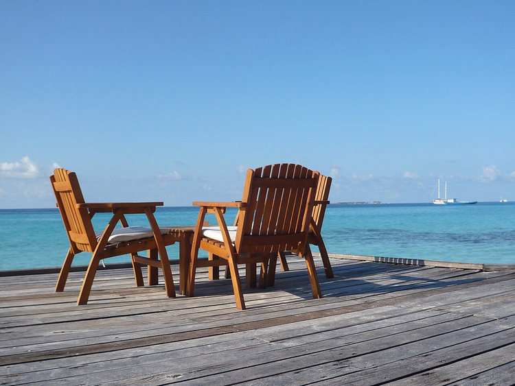 Houten deck met stoelen aan een turquoise lagune
