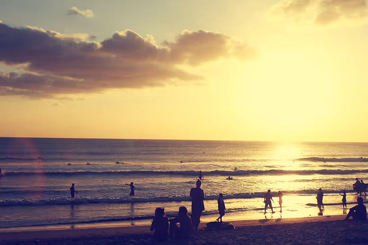 Solnedgang på Kuta-stranden, surfere og silhuetter av mennesker